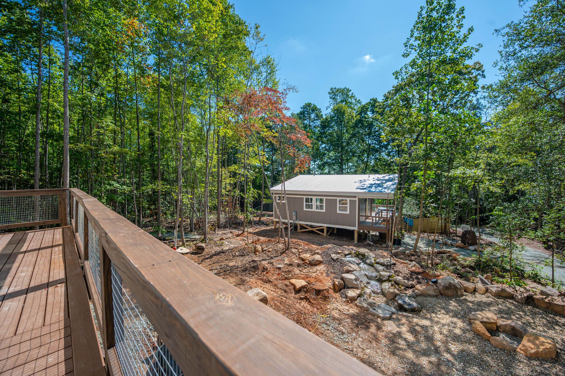 A cabin surrounded by a forest with a wooden deck and a small porch.