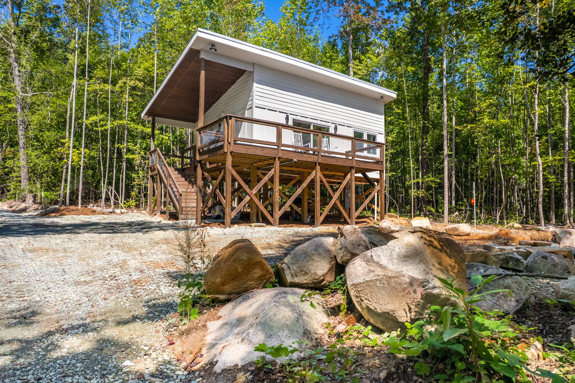 Een chalet met een houten terras en een overdekt bovenstuk, omgeven door een bos.