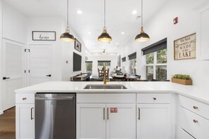 A modern kitchen with white cabinetry, stainless steel appliances, pendant lighting, and a large island. - Lakeside Luxury: Free Tickets, 6 BDRM with Private Hot Tub & Rooftop Deck with Lake Views! (Branson)