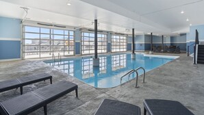 Una piscina interior amb finestres transparents, gandules i una escala.