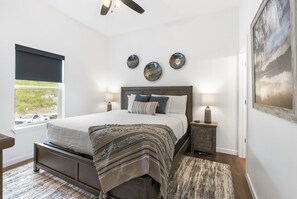 A bedroom with a bed, bedside lamps, a window with a view, and decorative wall art.