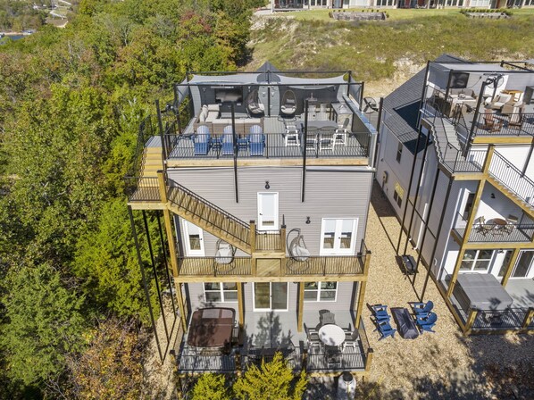 A multi-story house with a deck, outdoor seating, and a hot tub.
