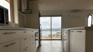 A kitchen with white cabinets, a microwave, and a view of a marina through a glass door.