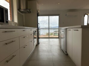 A kitchen with white cabinets, a microwave, and a view of a marina through a glass door.