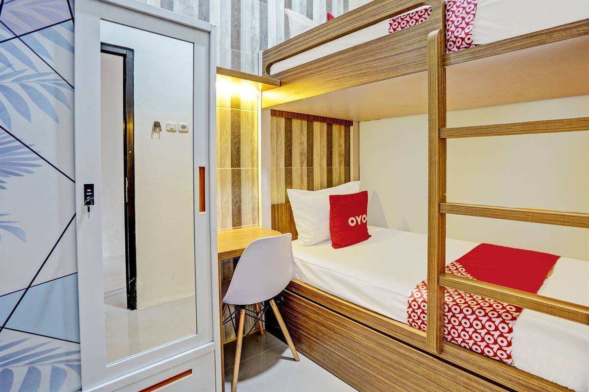 Ein kleines Zimmer mit einem Etagenbett, einem Schreibtisch und einem Stuhl.