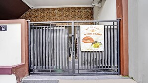 Une entrée fermée par un portail, sur laquelle est affiché un panneau publicitaire pour un restaurant et son menu.