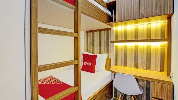 Un lit superposé avec un oreiller rouge, un bureau avec une chaise et une armoire en bois.