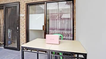 A table with a laptop and a chair outside a building with a brick facade and large windows.