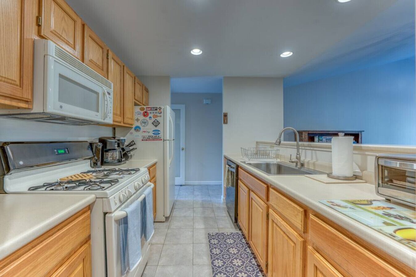 A kitchen with wooden cabinets, a white refrigerator, a stove, and a sink.