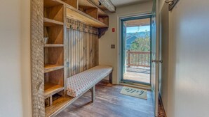 Un couloir avec un banc en bois, des étagères ouvertes et une porte donnant sur un balcon.