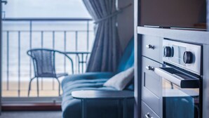A balcony with a view of the sea, a chair, and a bed with a dresser. - 17 Beach Court - 2 Bed Apartment - Saundersfoot (Saundersfoot)
