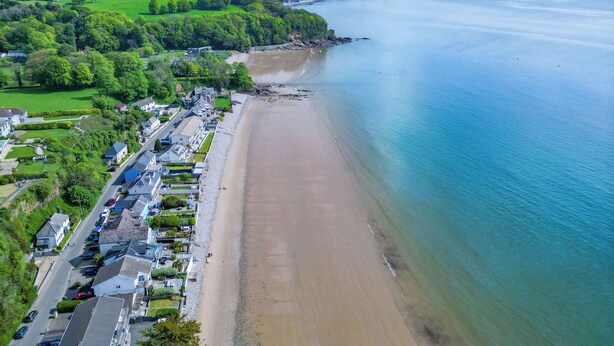 An aerial view of a coastal town with a sandy beach, residential buildings, and a clear view of the sea. - 17 Beach Court - 2 Bed Apartment - Saundersfoot (Saundersfoot)
