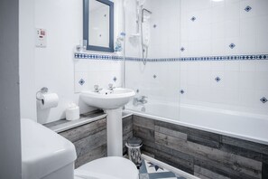 Un baño con lavamanos, inodoro y bañera blancos.
