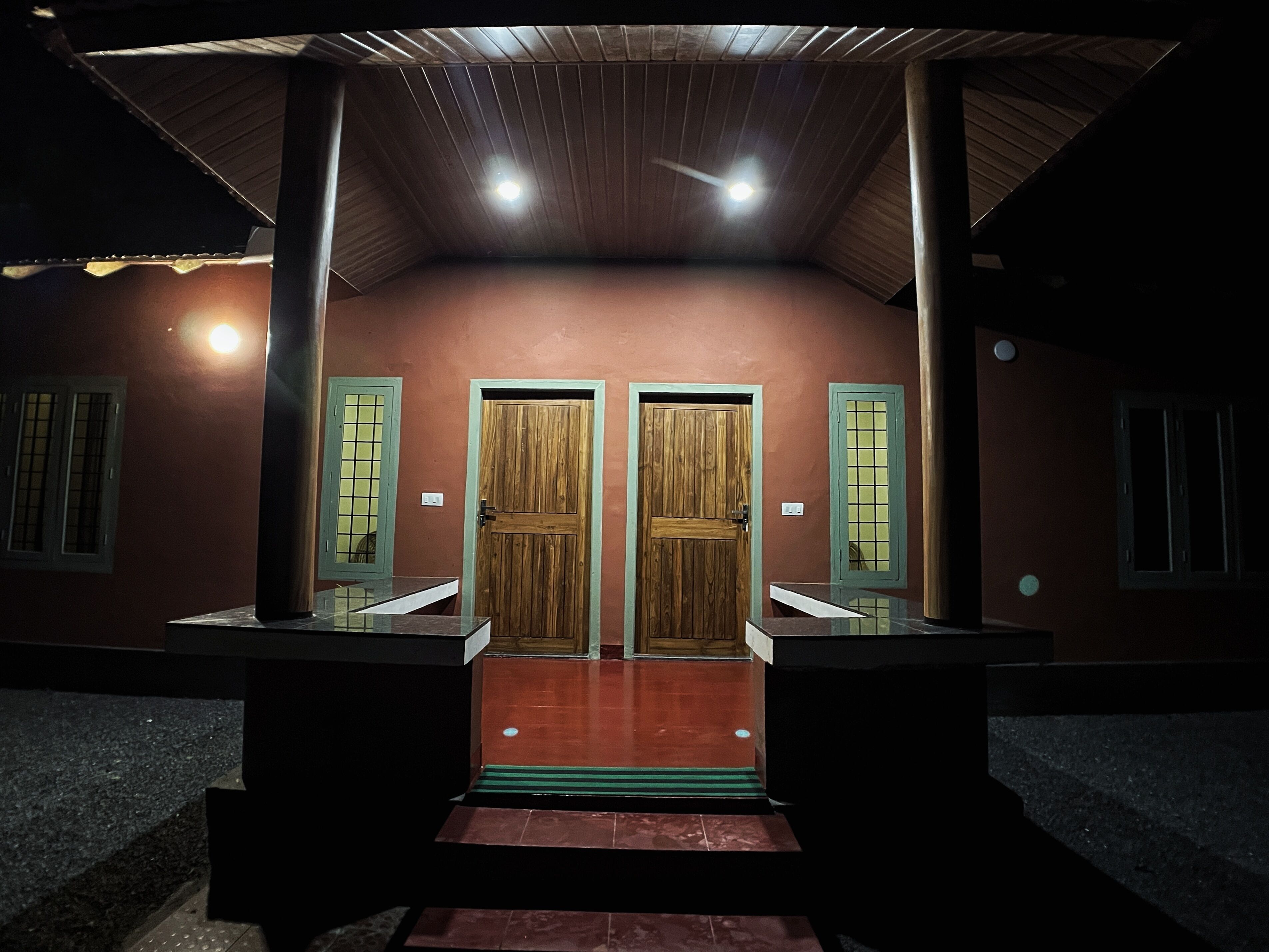 A building with two wooden doors, a tiled entrance, and a metal roof.
