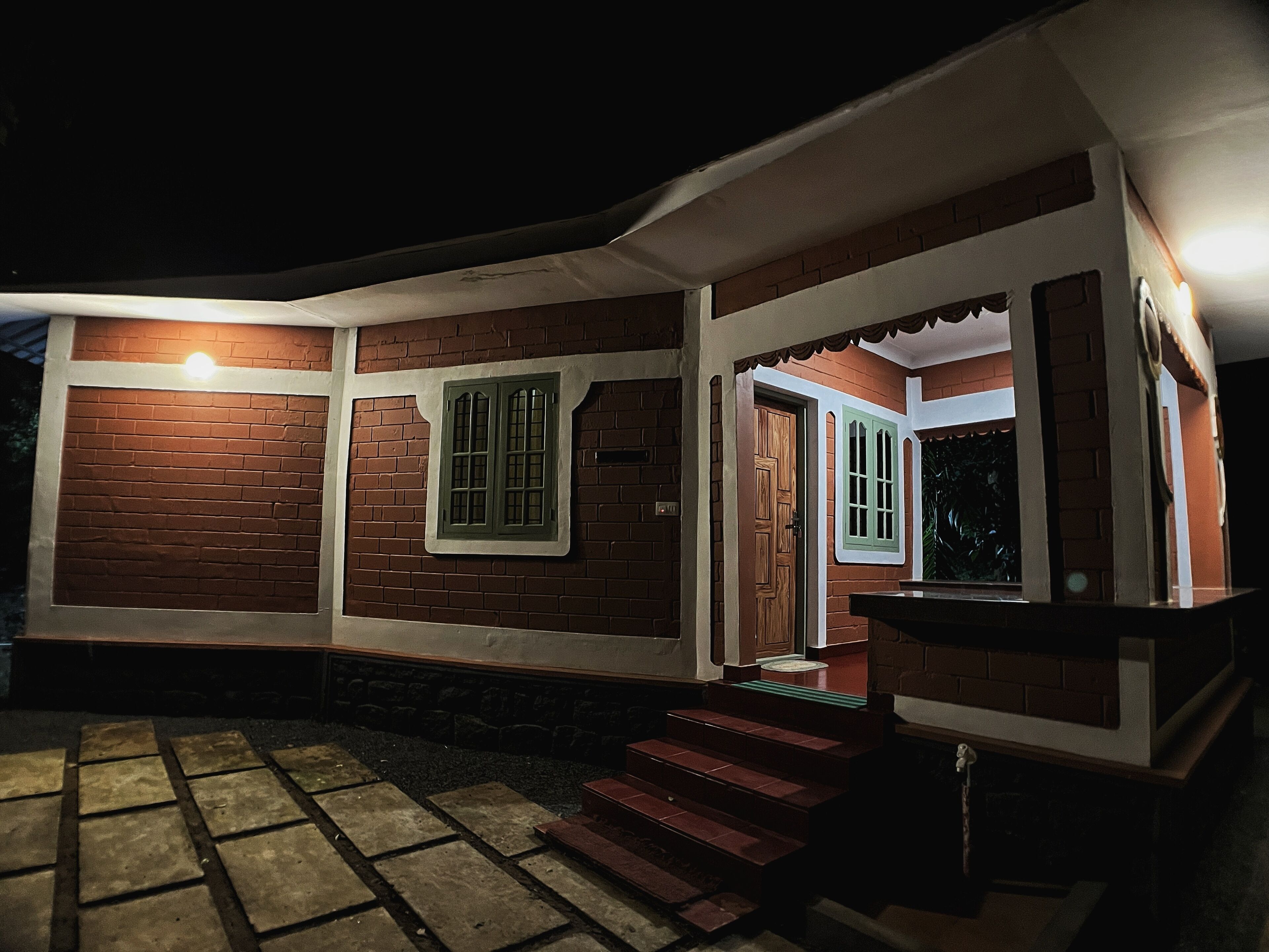 Una casa de ladrillo con un porche, una escalera que lleva a la entrada y un accesorio de iluminación sobre la puerta.