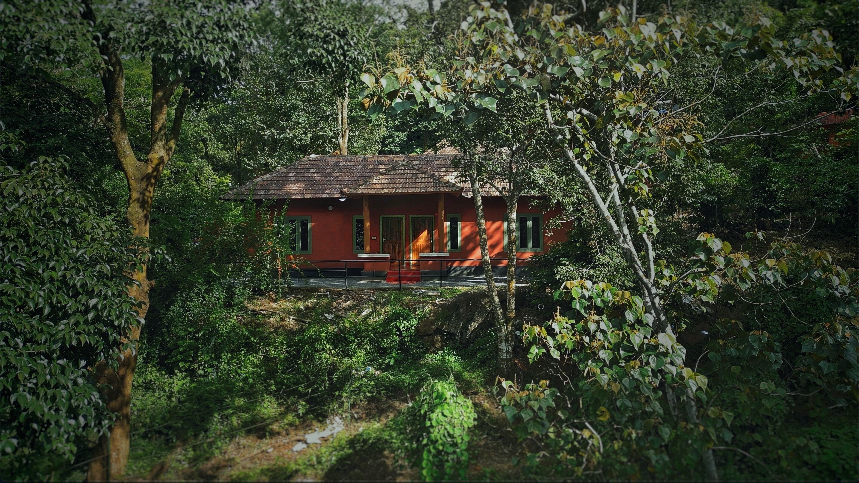 Una casa rossa circondata da vegetazione lussureggiante.