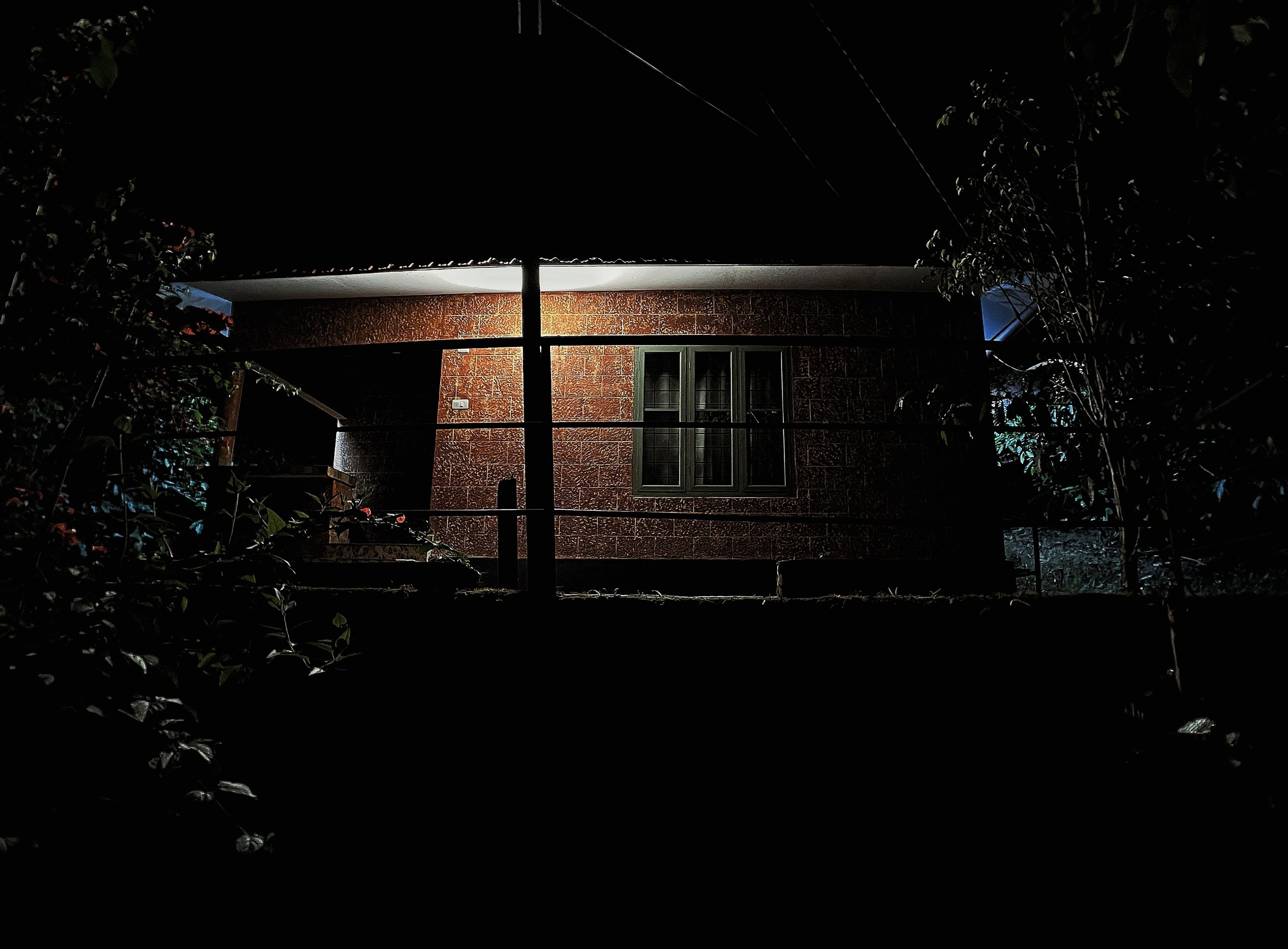 A brick house at night with a visible window and a door.