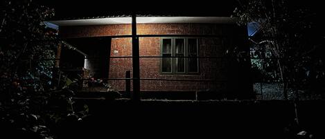 A brick house at night with a visible window and a door.