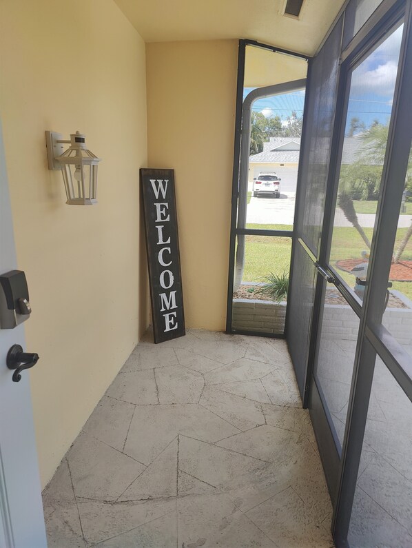A welcome sign, a door, and a view of a street with a car.