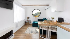 A modern kitchen with a round window, a dining area with a table and chairs, and a built-in fireplace.