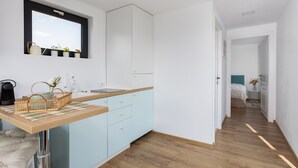 A modern kitchen with light blue cabinets, a wooden countertop, and a window above the sink.