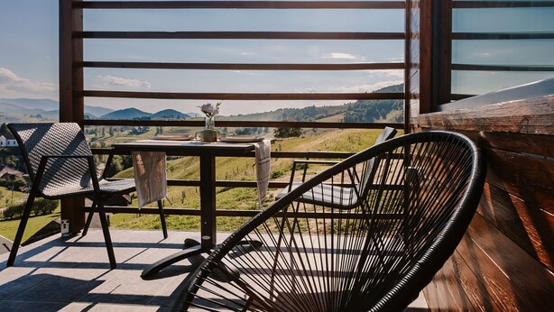 A wooden deck with a table and chairs overlooking a scenic landscape.