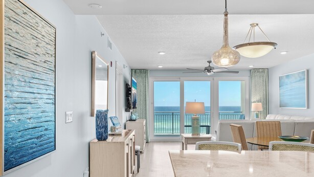 Eine moderne Küche mit Marmorarbeitsplatte, einem Essbereich mit Stühlen und Blick auf das Meer durch große Fenster.