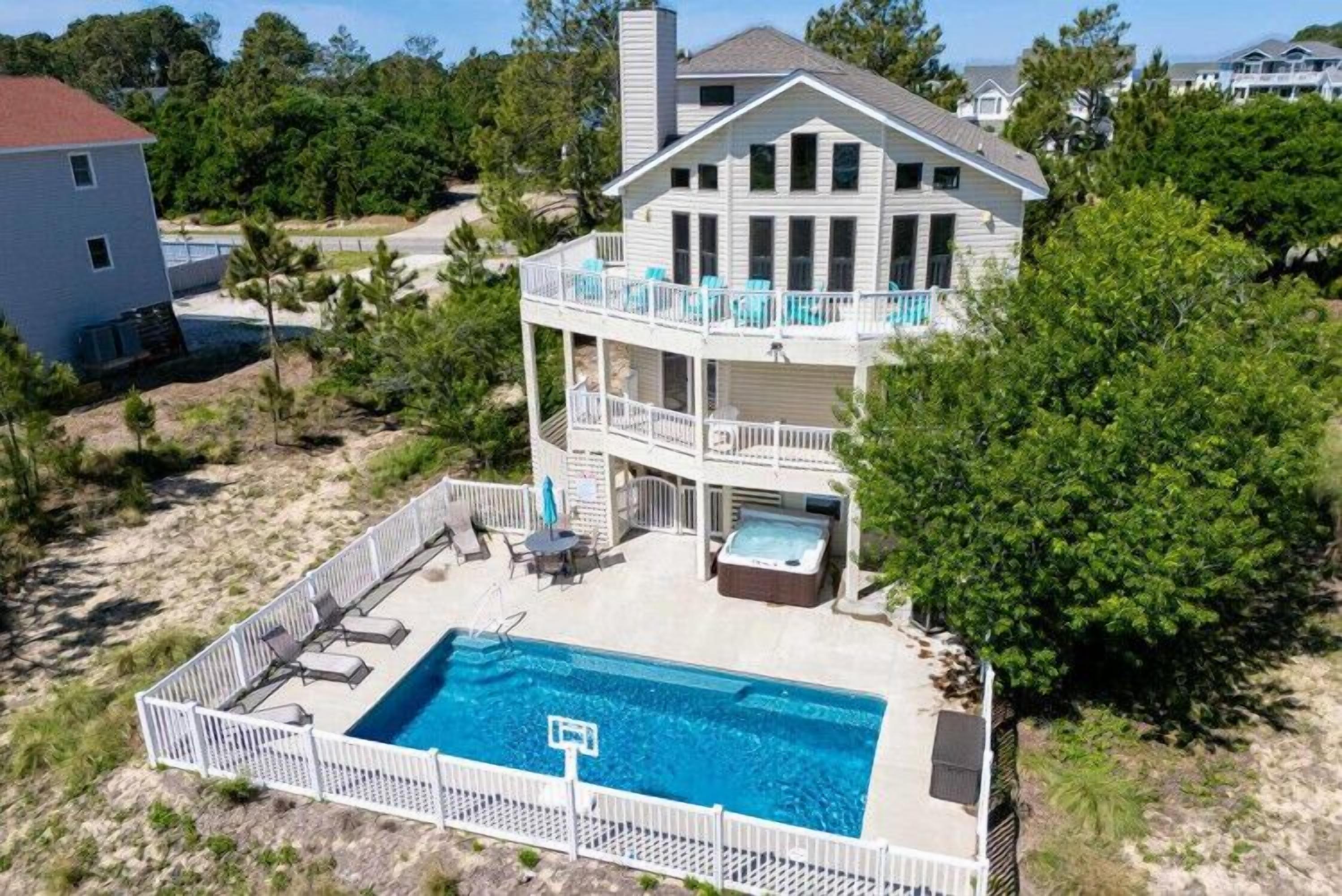 A two-story house with a pool, outdoor furniture, and a hot tub.