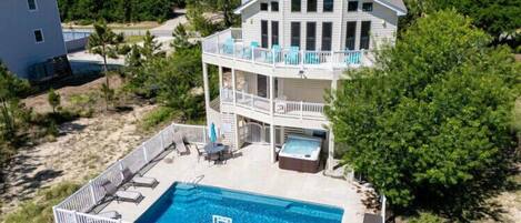 Una casa de dos pisos con piscina, muebles de exterior y jacuzzi.
