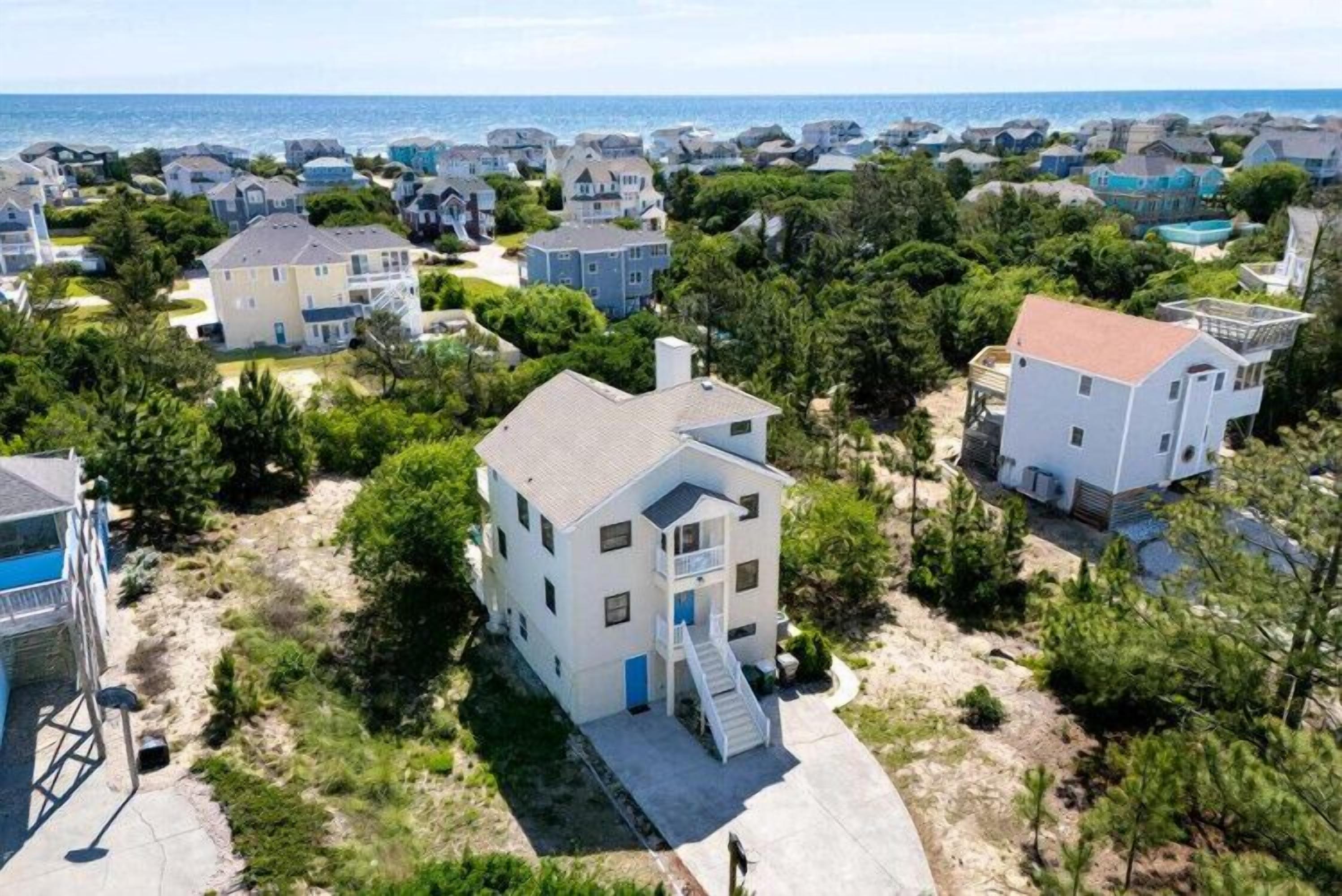 A residential area with houses, a clear sky, and a view of the sea.