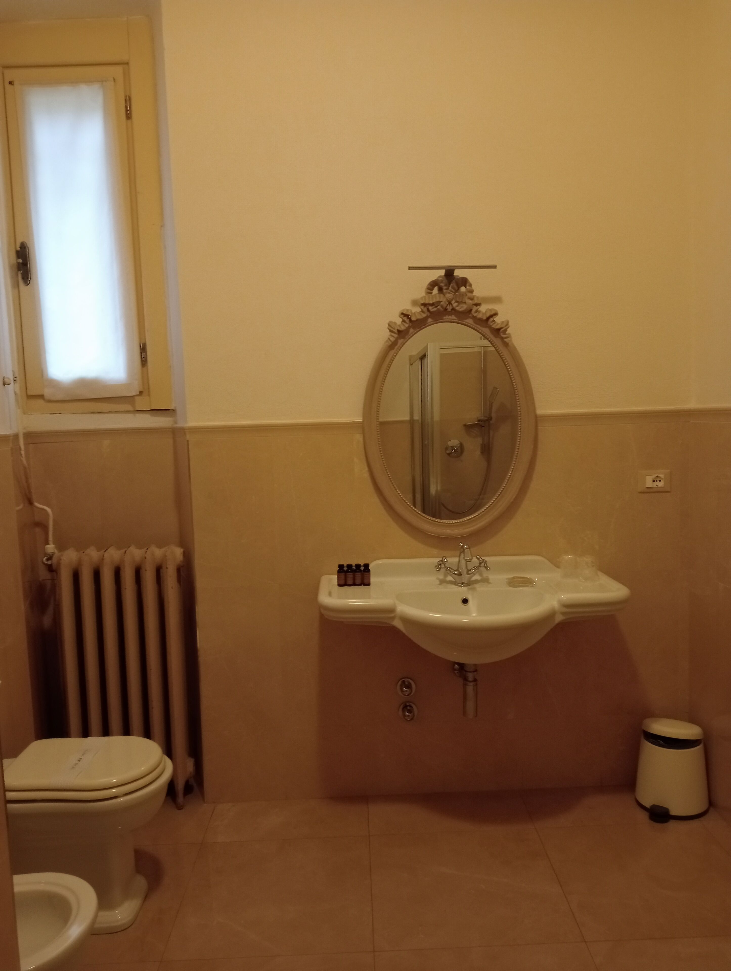 Een badkamer met toilet, wastafel, spiegel en radiator.