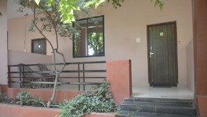 A building entrance with a wooden door marked '104', a staircase, and a small tree.