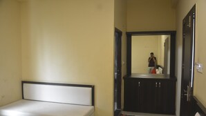 A room with a bed, a small table, a mirror, and a door leading to a bathroom.