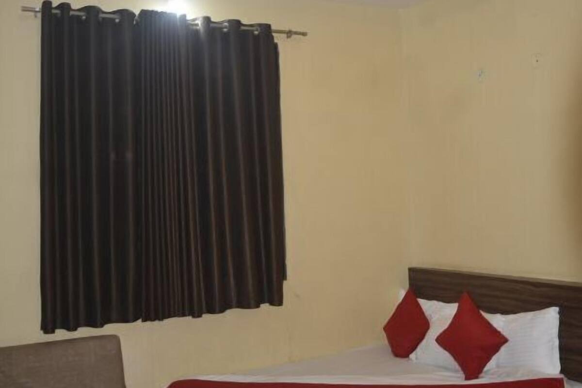 A hotel room with a bed, a chair, a ceiling fan, and curtains.