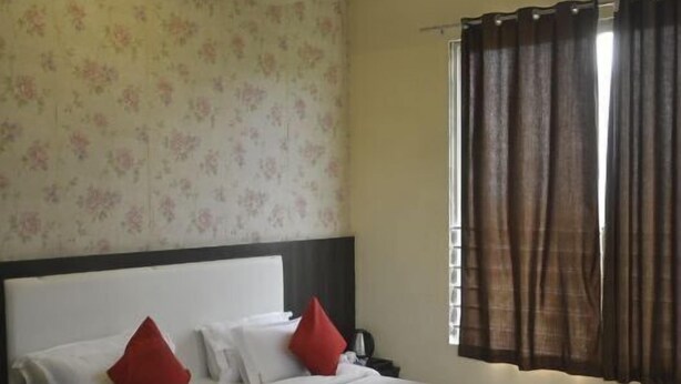 A bedroom with a large bed, a nightstand, a ceiling fan, and a window with curtains.
