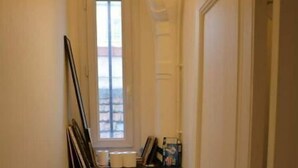 Un couloir étroit avec des toilettes, une fenêtre et une porte.