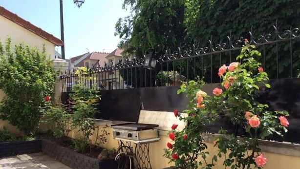 Une terrasse extérieure avec un barbecue, des jardinières en briques et une clôture en métal.