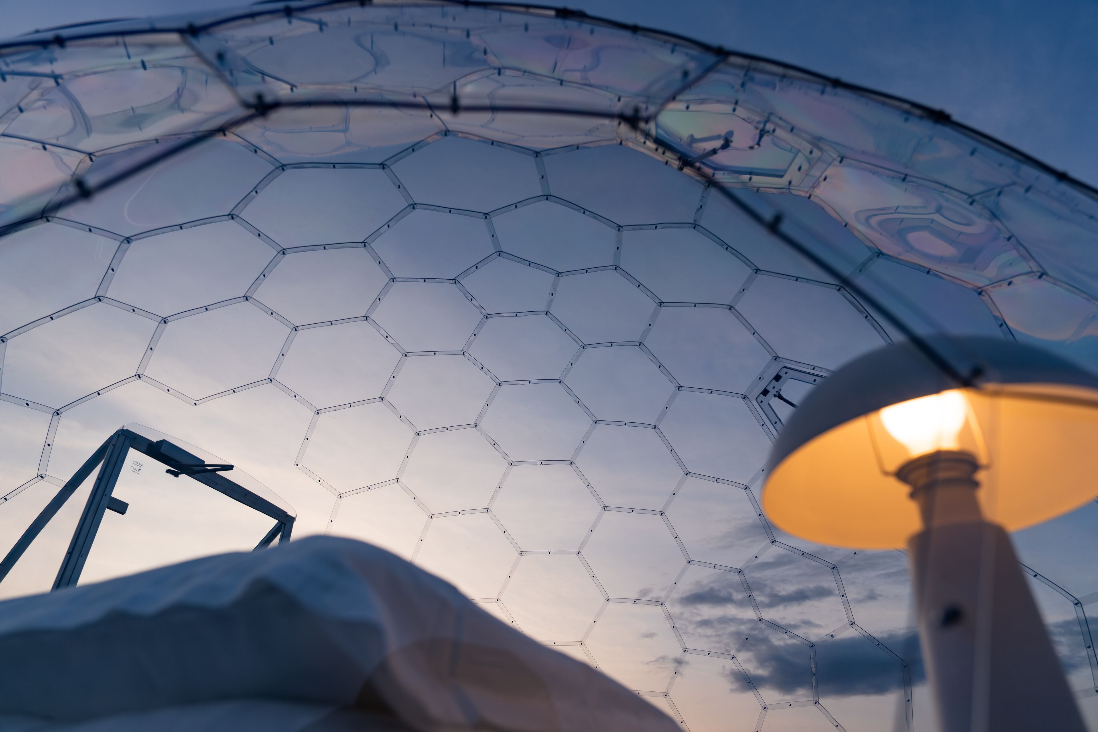 A dome structure with a hexagonal pattern, a lamp post, and a partial view of a bed.