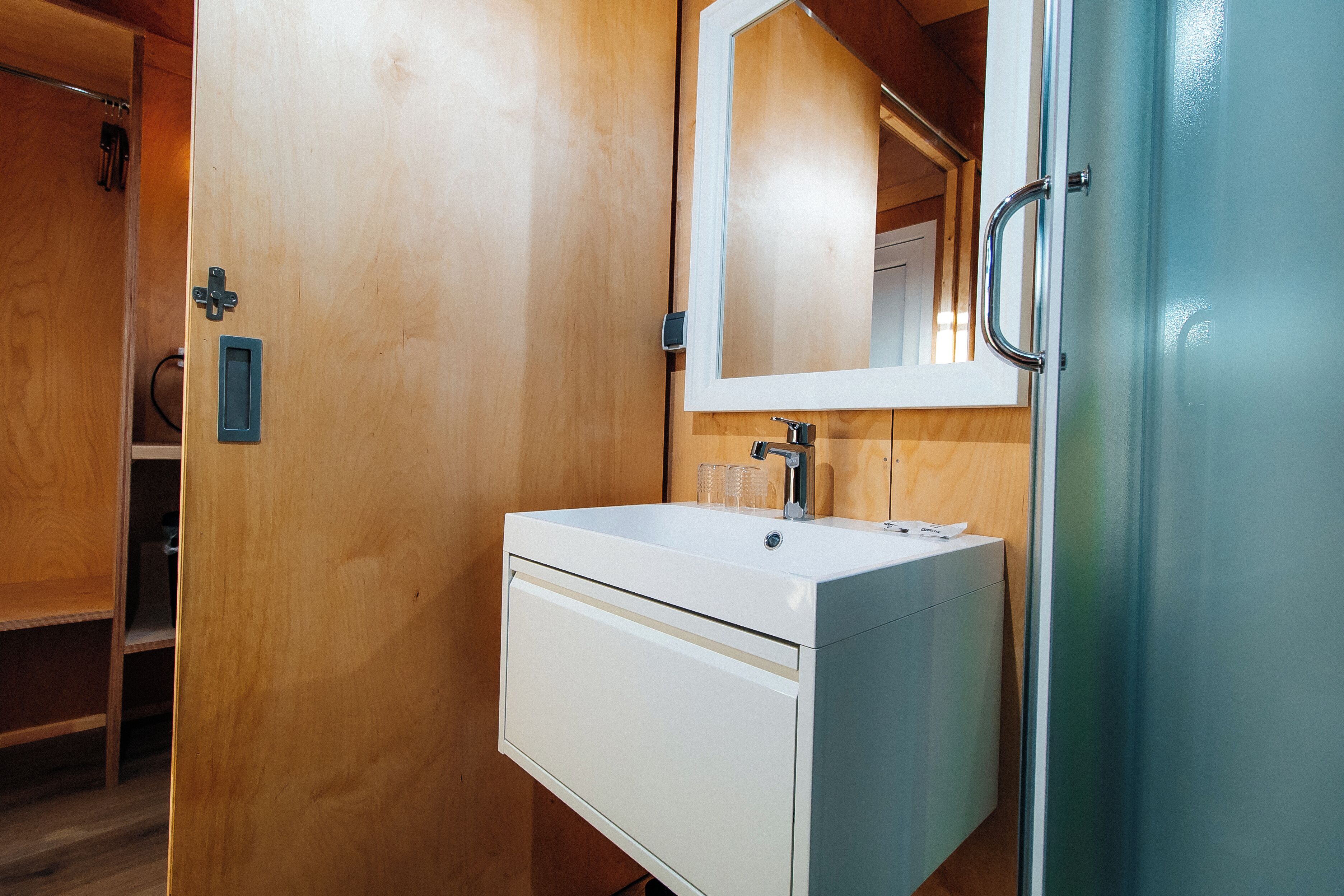 A compact bathroom with a white sink, a mirror, and a door.