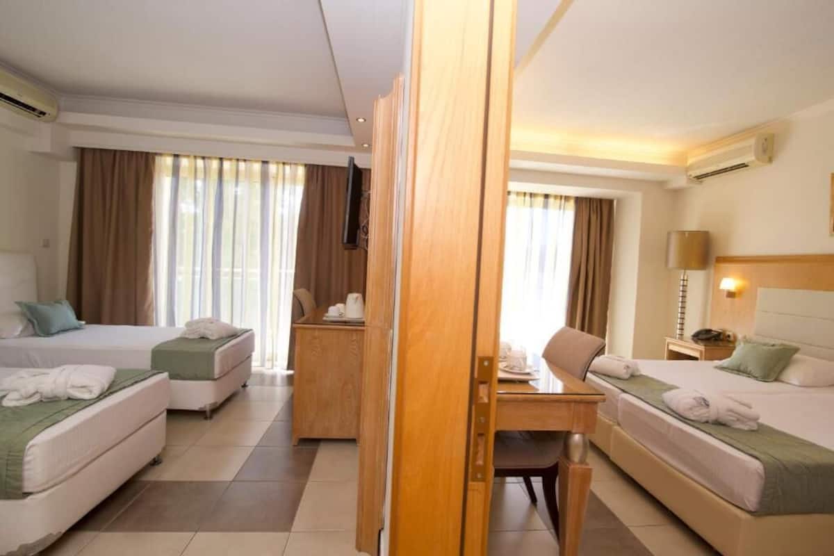 A hotel room with two beds, a desk, and a chair.