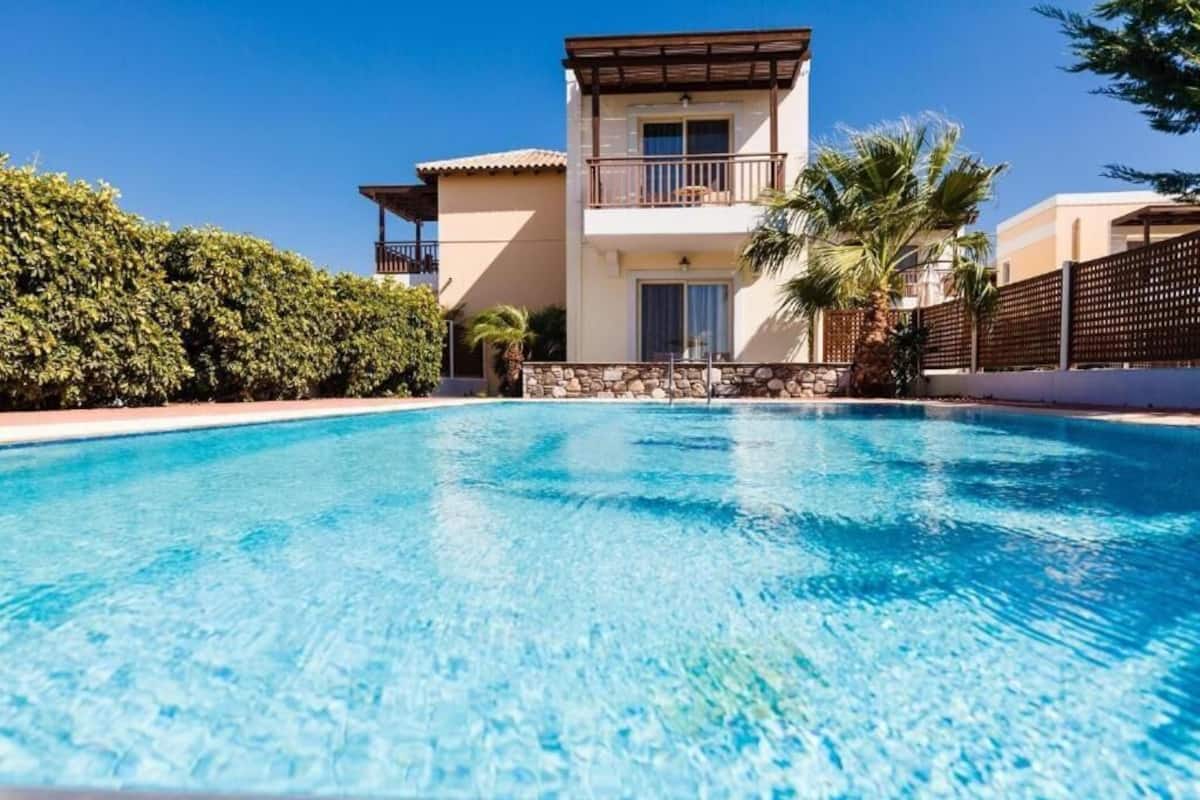 A two-story house with a swimming pool in front.