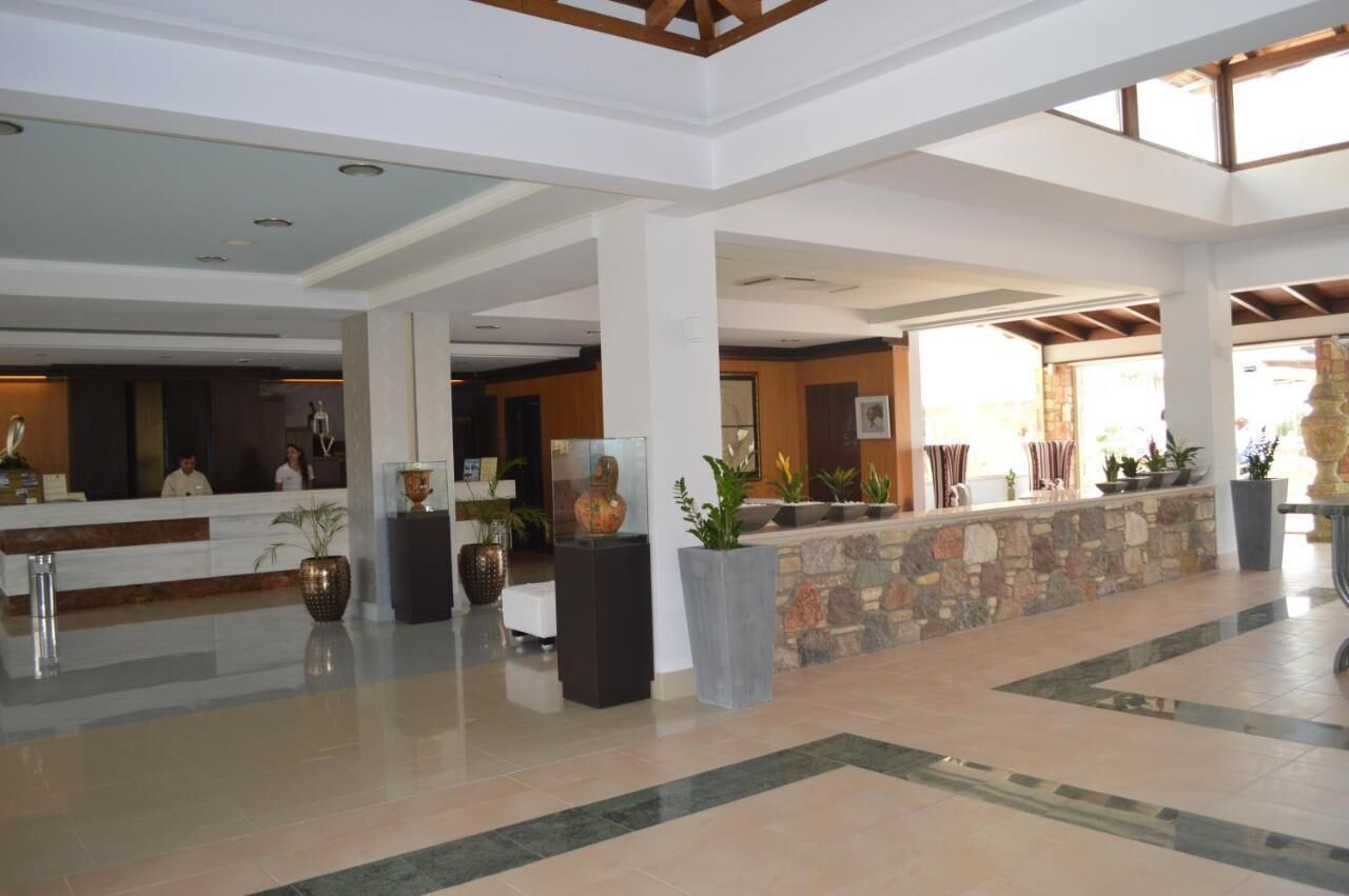 A spacious lobby with a reception desk, large potted plants, and a stone wall.