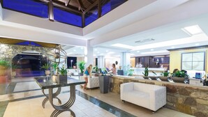 A spacious lobby with a central marble table, seating areas, and a reception desk. - Natura Park Village Hotel & Spa  (Kos)