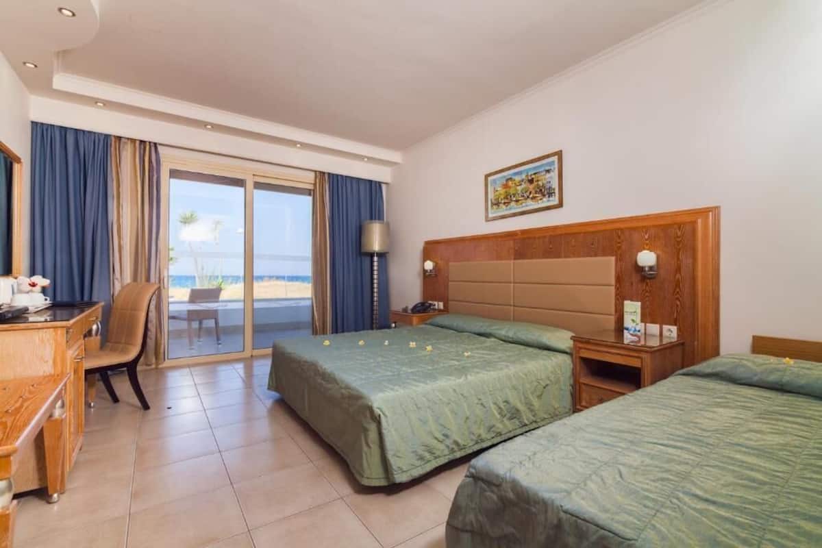 A hotel room with a bed, a desk, a chair, a lamp, and a painting on the wall.
