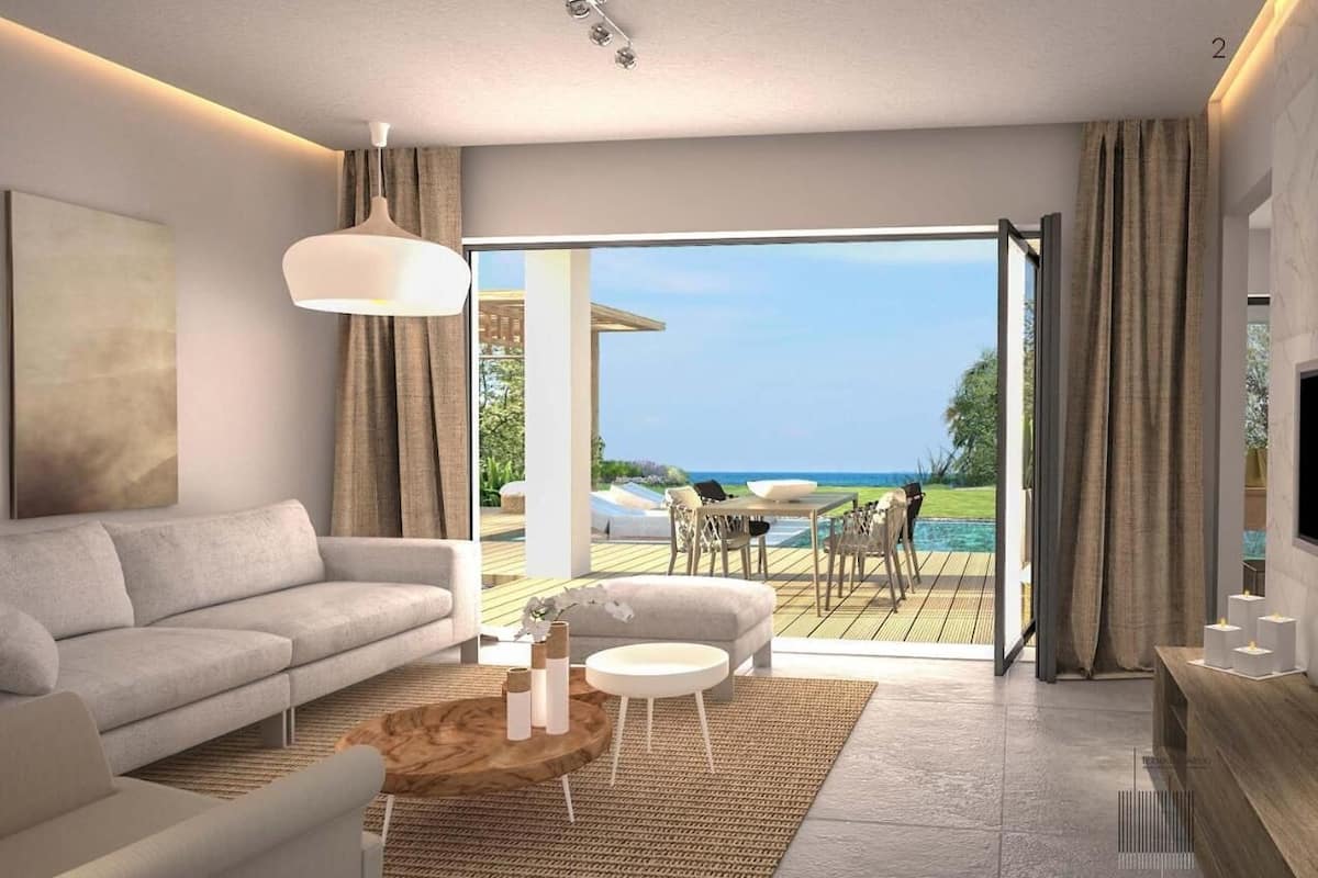 A modern living room with a sofa, coffee table, and a view of an outdoor deck and pool.