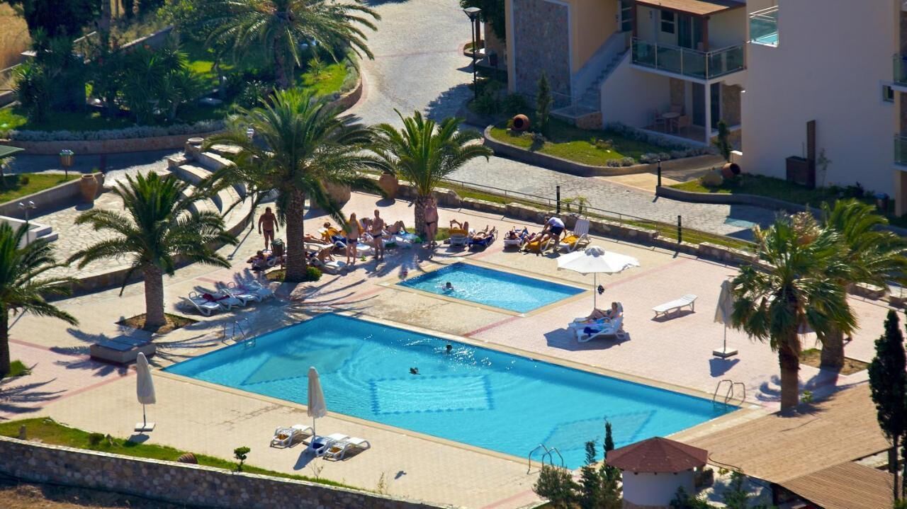 Un resort con dos piscinas, palmeras y sillas de descanso.