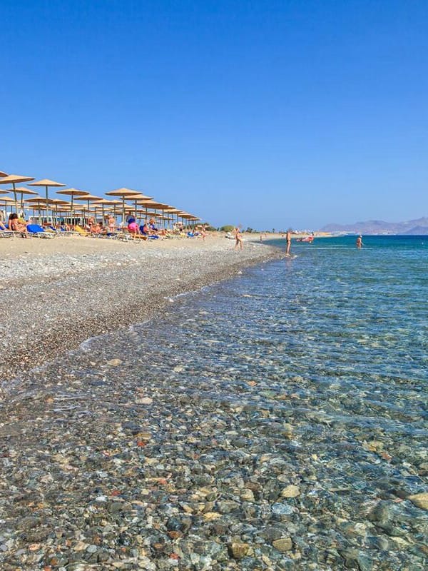 Relax on the beach with comfortable sun loungers and umbrellas, surrounded by calm waters and majestic mountains.