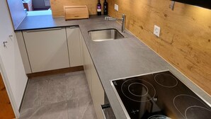 A modern kitchen with a built-in stove, a sink, and wooden cabinetry.