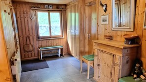 A wooden cabin interior with a bench, a small table, a cabinet, and a mirror on the wall.