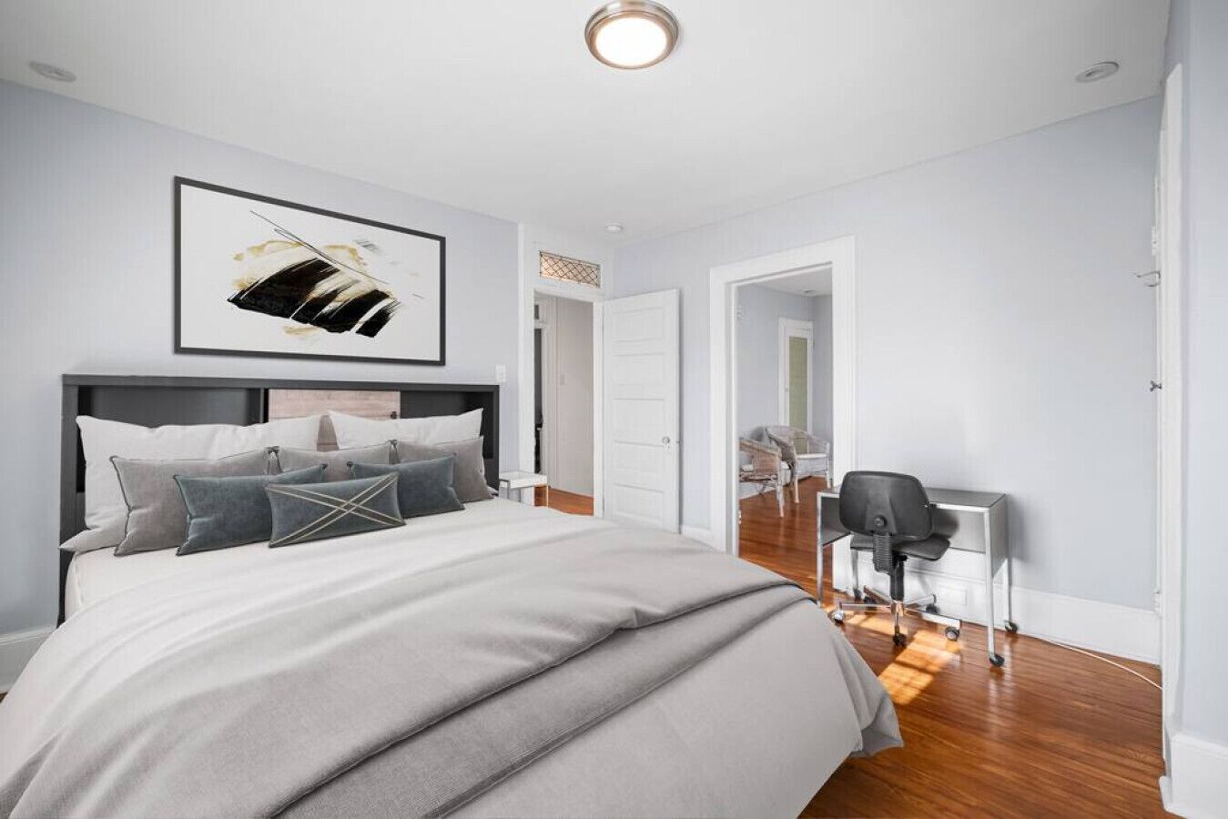 A modern bedroom with a large bed, a desk, and a chair.